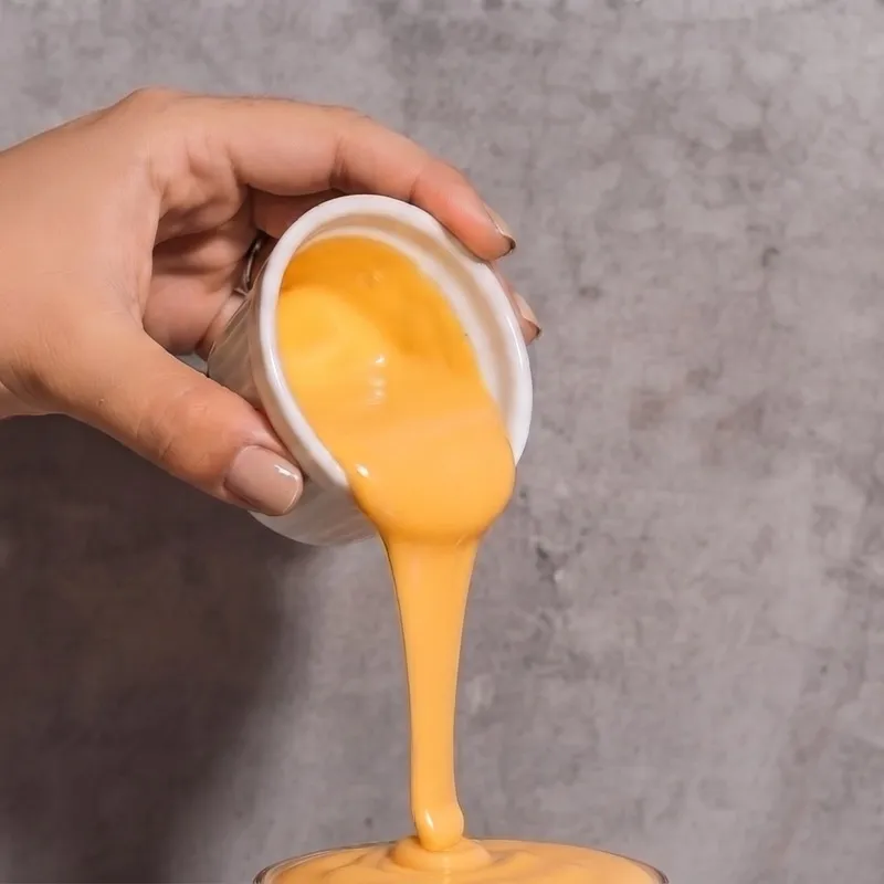 Cheddar cayendo sobre un vaso de choclo