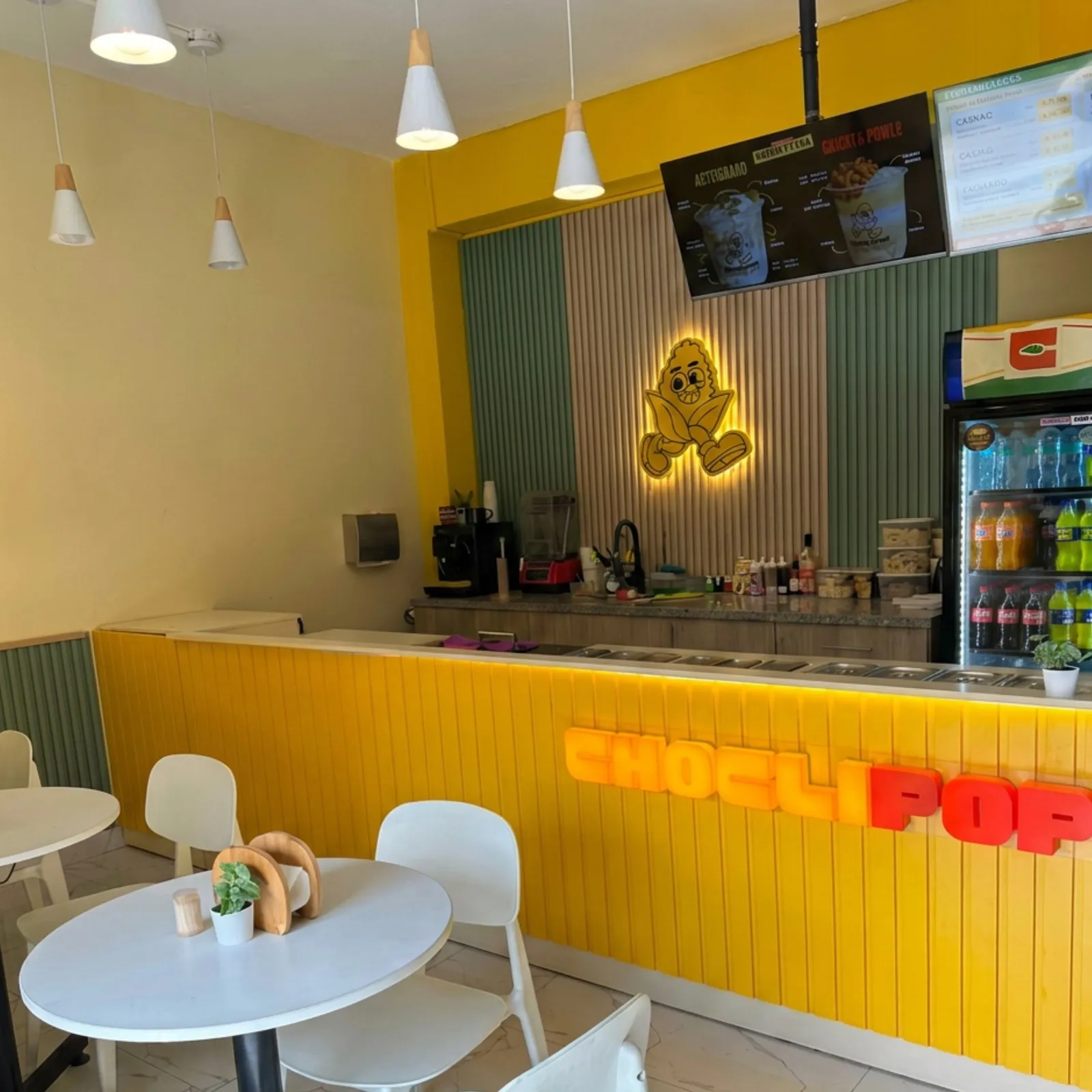 Salón de Choclipop: barra amarilla con el letrero luminoso y mesas para sentarse